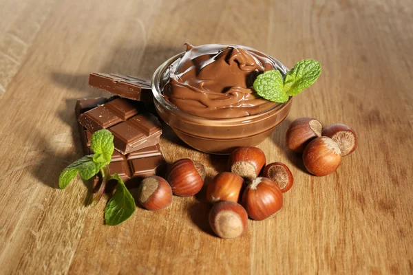 Sweet chocolate hazelnut spread with whole nuts and mint on wood background — Stok Foto