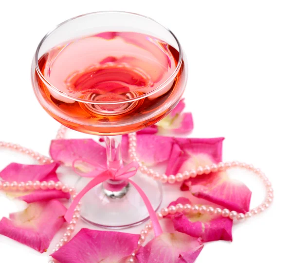 Σύνθεση με ροζ λάμψη κρασί σε ποτήρι και ροδοπέταλα απομονωθεί σε λευκό — Φωτογραφία Αρχείου