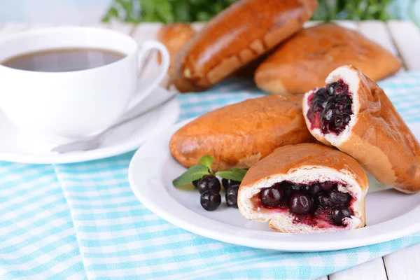 Fresh baked pasties with currant on plate on table close-up — Stock Photo, Image