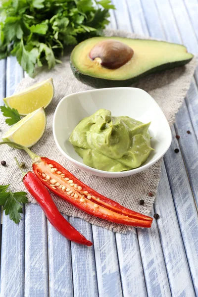 Fresh guacamole in bowl on wooden table — Stock Photo, Image