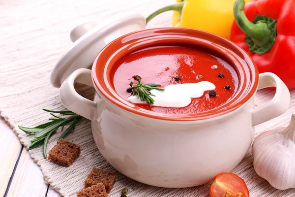 Вкусный томатный суп и овощи на деревянном столе — стоковое фото