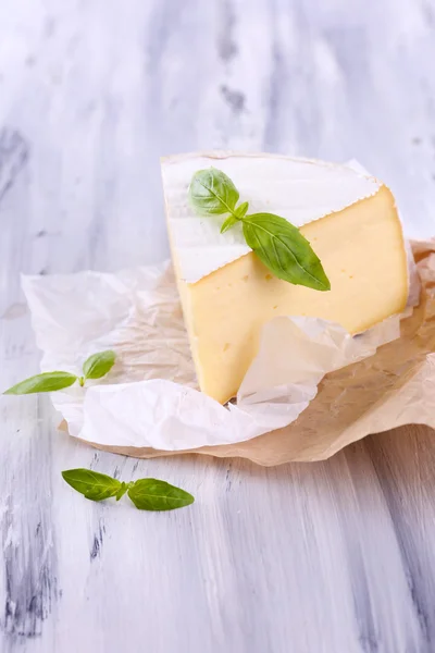 Schmackhafter Camembert-Käse mit Basilikum, auf Holztisch — Stockfoto