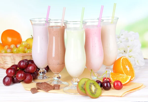 Batidos de leite com frutas na mesa no fundo azul claro — Fotografia de Stock