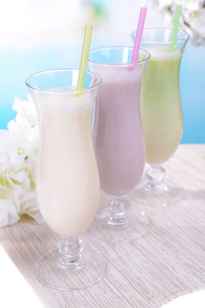 Frullati di latte sul tavolo su sfondo azzurro — Foto Stock