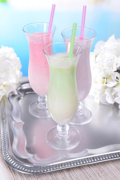 Milk shakes on table on light blue background — Stock Photo, Image