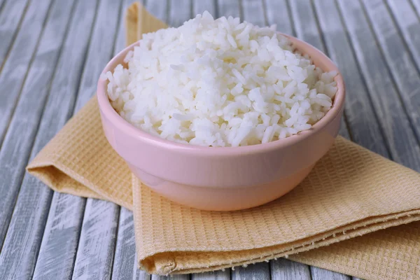 Arroz cozido em tigela no fundo de madeira — Fotografia de Stock