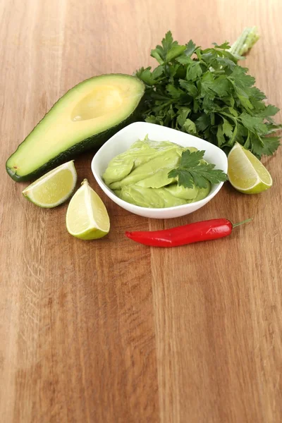 Fresh guacamole in bowl on wooden table — Stock Photo, Image