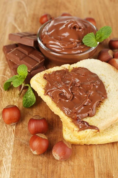 Bröd med söt choklad hasselnöt sprida på trä bakgrund — Stockfoto