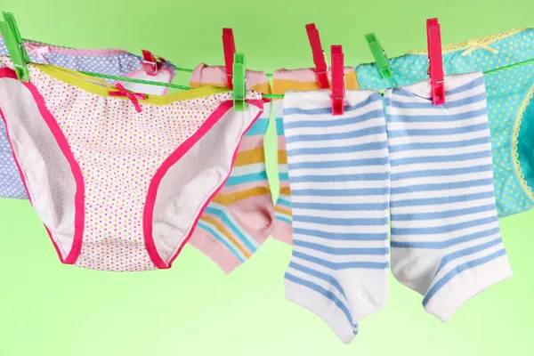 Baby clothes hanging on clothesline, on color background — Stock Photo, Image