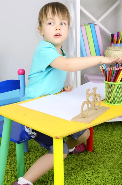 Klein meisje trekt vergadering aan tafel op kamer — Stockfoto