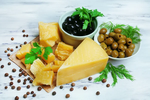 Parmesan cheese, fresh herbs and olives on wooden background — Stock Photo, Image