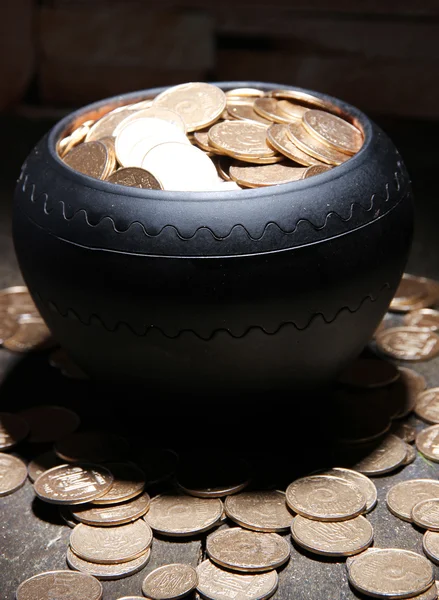 Golden coins in ceramic pot, on wooden table on dark background — Stock Photo, Image