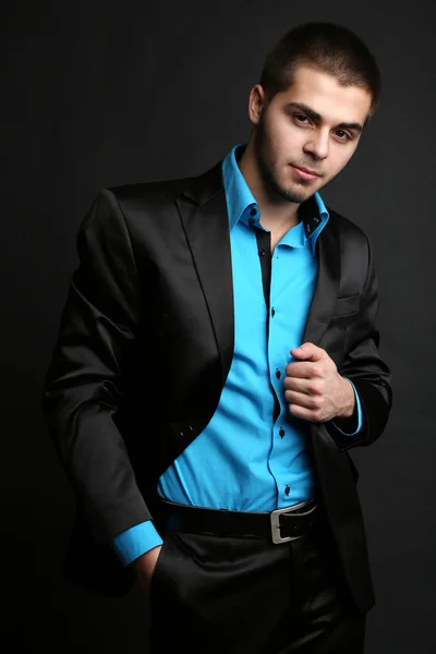 Schöner junger Mann im Anzug auf dunklem Hintergrund — Stockfoto