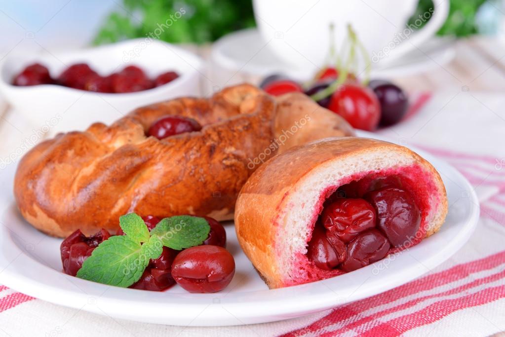 Fresh baked pasties with cherry on plate on table close-up