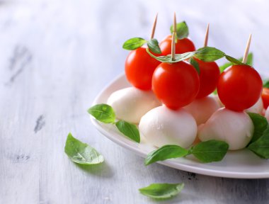 ahşap masa tabakta domates ve fesleğen ile lezzetli mozzarella peyniri