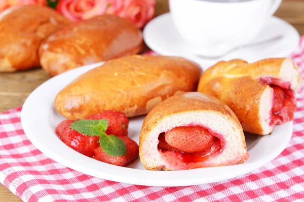 Vers gebakken pasteitjes met aardbeien op de plaat op tabel close-up — Stockfoto