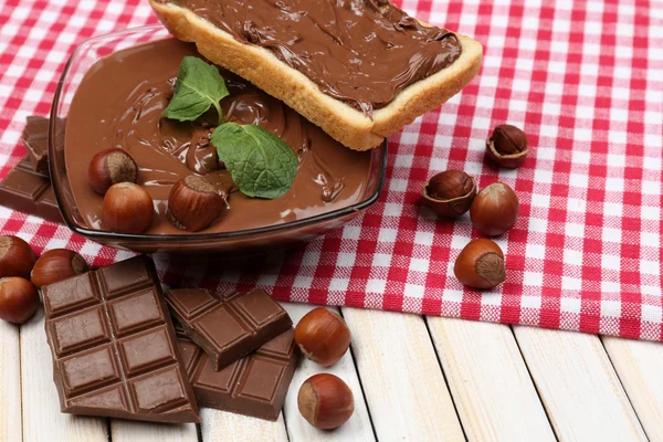Sweet chocolate hazelnut spread with whole nuts and mint on wood background — Stok Foto