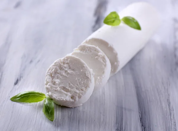 Tasty bushe cheese with basil, on wooden table — Stock Photo, Image