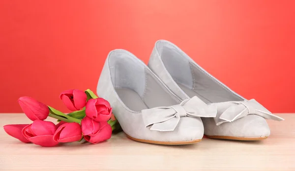 Beautiful grey female shoes and flowers on red background — Stock Photo, Image