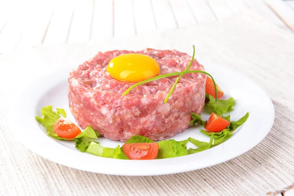 Delicious steak tartare with yolk on plate on table close-up — Stock Photo, Image