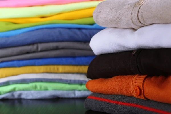 Pila di vestiti colorati, su sfondo scuro — Foto Stock