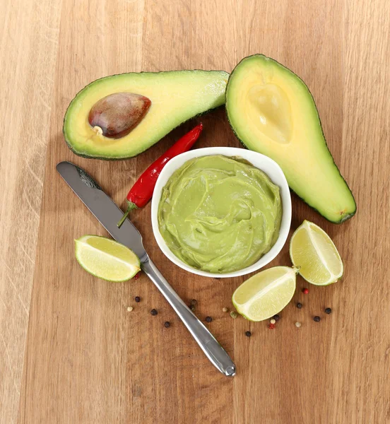 Fresh guacamole in bowl on wooden table — Stock Photo, Image