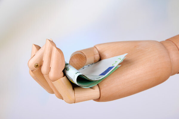 Деньги в деревянной руке, на светлом фоне
