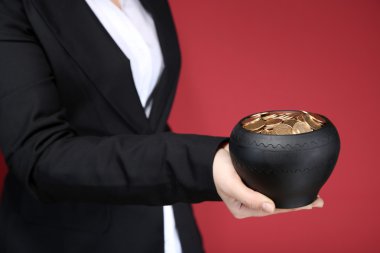 Seramik pot eller, renkli arka plan üzerinde altın paralar ile