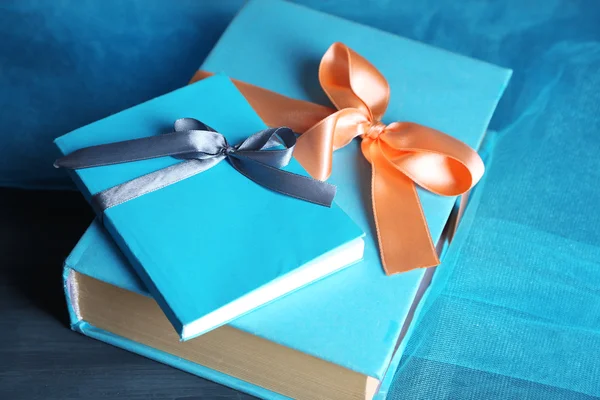Koyu arka plan üzerinde ahşap masa üzerinde renk kurdele ile sarılmış kitaplar — Stok fotoğraf