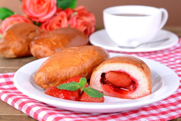 Fresh baked pasties with strawberries on plate on table close-up — Stock Photo, Image