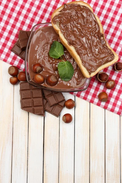 Sweet chocolate hazelnut spread with whole nuts and mint on wood background — Stok Foto