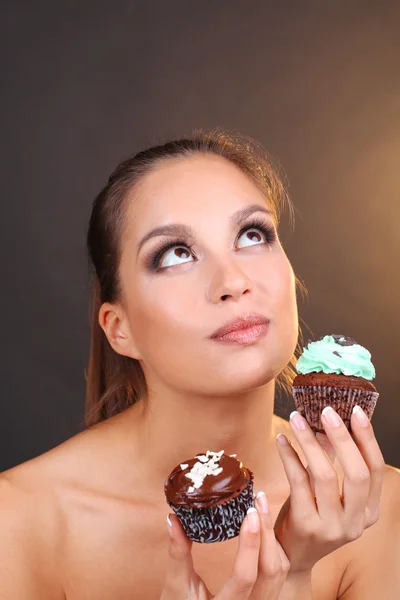 Portrait de belle jeune fille avec cupcake au chocolat sur fond brun — Photo