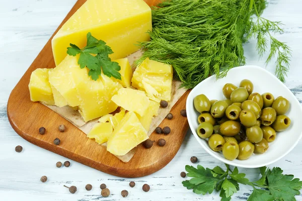 Parmesan cheese, fresh herbs and olives on wooden background — Stock Photo, Image