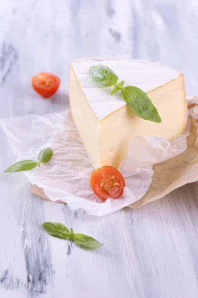 Smakelijke camembert kaas met basilicum en tomaat, op houten tafel — Stockfoto