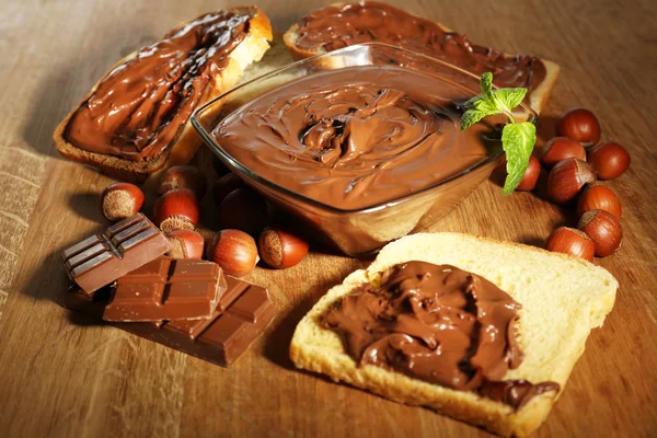 Avellana de chocolate dulce untada con nueces enteras y menta sobre fondo de madera —  Fotos de Stock