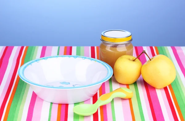 Jar of baby puree with plate and spoon on napkin on blue background — Stock Photo, Image