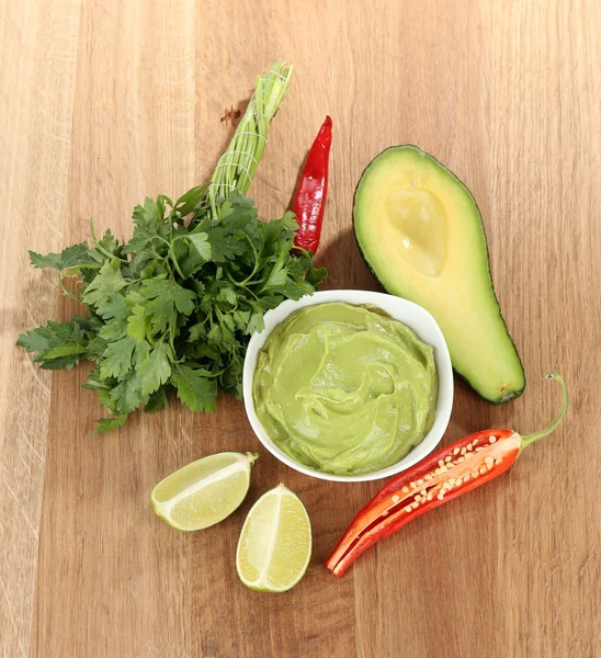 Fresh guacamole in bowl on wooden table — Stock Photo, Image