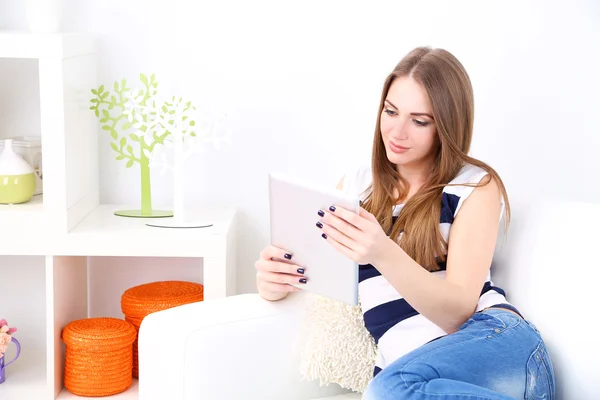 Junge Frau ruht sich mit Tablet auf Sofa zu Hause aus — Stockfoto