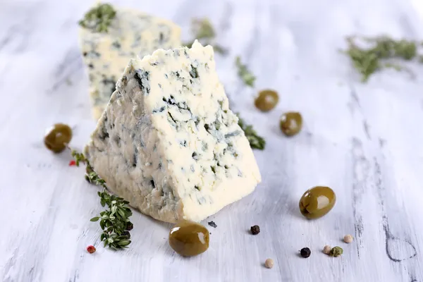 Tasty blue cheese with thyme and olives on wooden table — Stock Photo, Image