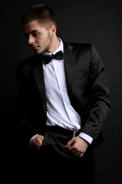 Pohledný mladý muž v obleku na tmavém pozadí — Stock fotografie