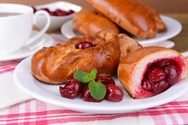 Fresh baked pasties with cherry on plate on table close-up — Stock Photo, Image