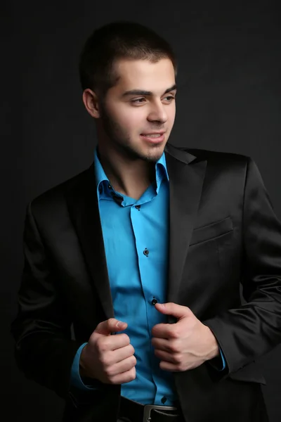 Handsome young man in suit on dark background — Stock Photo, Image