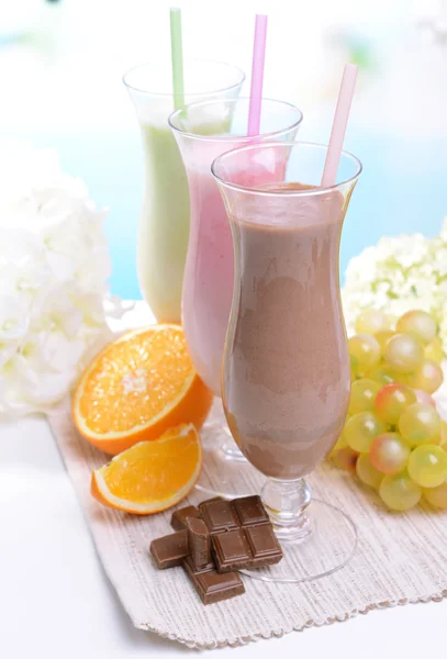 Batidos de leite com frutas na mesa no fundo azul claro — Fotografia de Stock