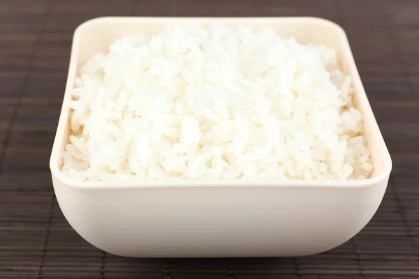 Arroz cocido en tazón sobre fondo de bambú — Foto de Stock