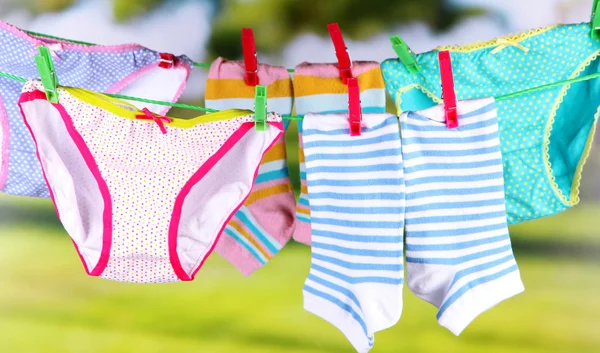 Babykläder hänger på klädstreck, på ljus bakgrund — Stockfoto