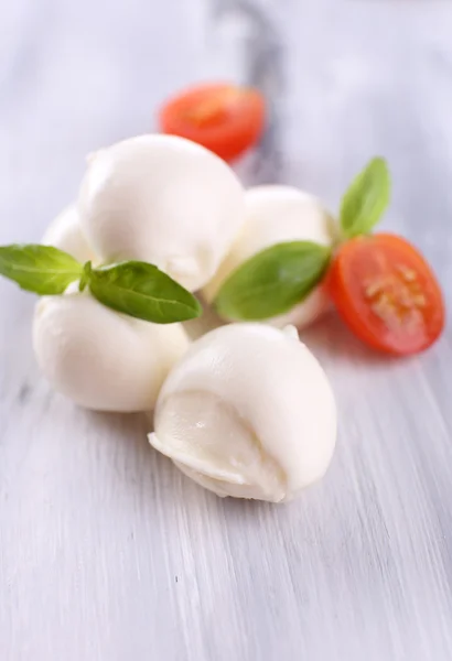 Tasty mozzarella cheese with basil and tomatoes, on wooden table — Stock Photo, Image