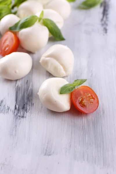 Queijo mussarela saboroso com manjericão e tomate, sobre mesa de madeira — Fotografia de Stock