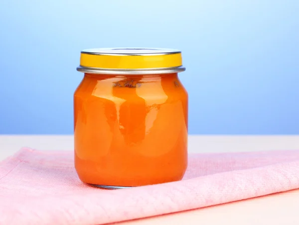 Glas Babypüree auf Serviette auf blauem Hintergrund — Stockfoto