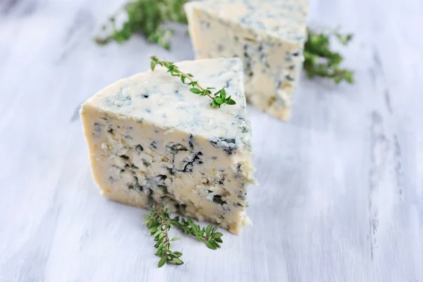 Smakelijke blauwe kaas met tijm op houten tafel — Stockfoto