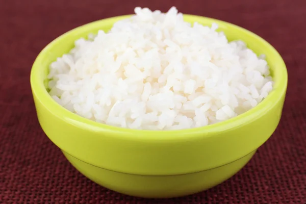 Gekookte rijst in kom op rode achtergrond — Stockfoto